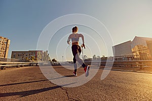 A woman runner jogs on a bridge in the city