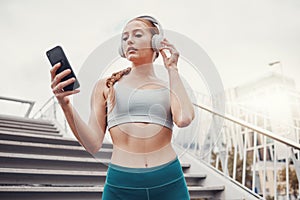 Woman, runner and phone with headphones for music, radio and web texting on chat app by stairs. Gen z girl, urban