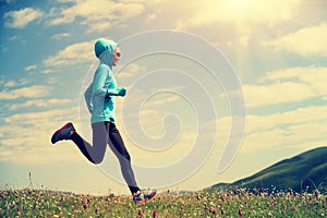 woman runner running on grassland mountain top