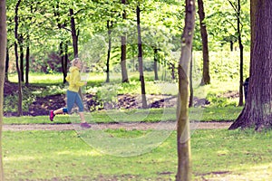 Woman runner running jogging in green summer park and woods