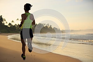 Woman runner running on sunrise beach