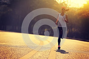 Woman runner running on sunrise road