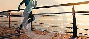 Woman runner running on sunrise seaside boardwalk