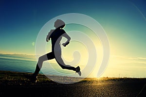 Woman runner running on sunrise seaside road