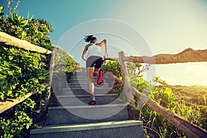 Woman runner running upstairs on mountain top
