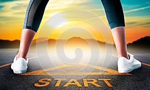 Woman runner standing on a start sign ready to run to goal and freedom on sunset sky for motivation begining concept photo