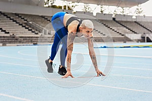 Woman, runner and start for track, exercise and warm up in stadium or field for fitness. Female athlete, training and