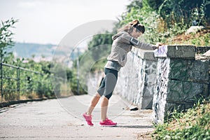 Woman runner stretching against rock wall