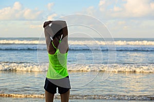 Woman runner stretching legs before running on sunrise seaside