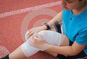 Woman runner suffering from pain in legs be injured,Hand touching her knee after jogging on track running