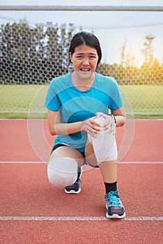 Woman runner suffering from pain in legs be injured,Hands touching her knee after jogging and workout outdoor on track running