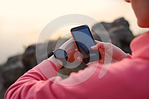 Woman Runner Syncing Fitness Data between the Smartwatch and Smartphone after Workout. Sports and Technology Concept