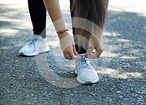 Woman runner tying her sneakers shoes. Outdoors