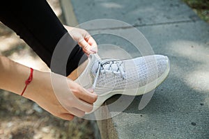 Woman runner tying her sneakers shoes. Outdoors