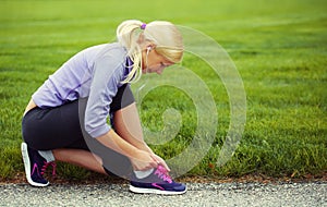 Una donna corridore legame correre calzature. bionda Attraverso erba 