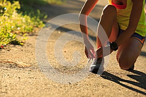 woman runner tying shoelace on morning tropical forest trail