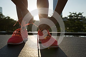 woman runner tying shoelace before running