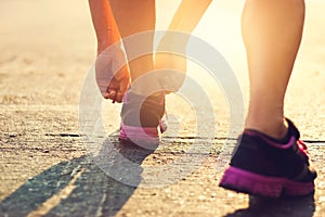 Woman runner tying shoelaces in the morning