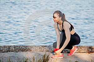 Woman runner tying shoelaces on sneakers on beach