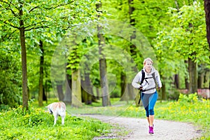 Woman runner walking with dog in summer park