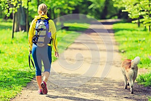 Woman runner walking with dog in summer park