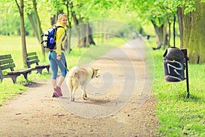 Woman runner walking with dog in summer park