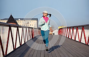 Woman runnig on a wooden bridge, cardio exercise outdoors
