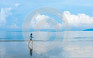 Woman running along the beach of the sea with beautiful sky and blue sea background, healthy lifestyle outdoor exercise concept