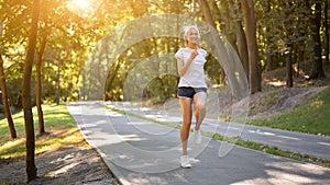 Woman running asphalt road summer park