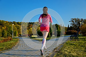 Woman running in autumn park, beautiful girl runner jogging outdoors