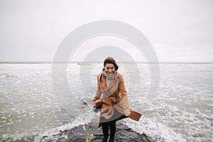 Woman running away from the waves of North Sea. Female afraid to be wet in cold weather