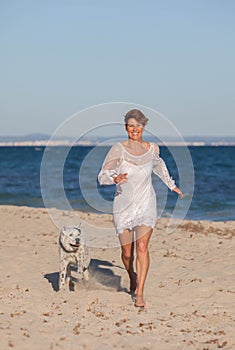 Woman running on beach with pet dog