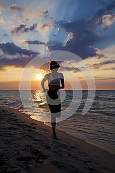 Woman running on the beach during sunset.