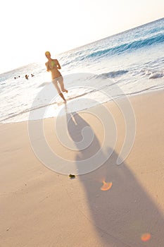 Woman running on the beach in sunset.