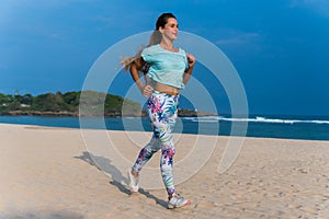 Woman running on beach at sunset. Beautiful fitness caucasian girl exercising outdoors on sea background. Caucasian fit