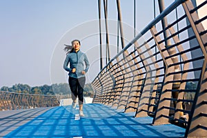 Woman running on the bridge on a sunny day