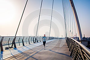 Woman running on the bridge on a sunny day