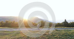 Woman running on a countryside road at sunset.