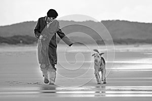 Woman running on deserted beautiful beach with pet dog