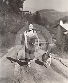 Woman running on dirt road with her dog