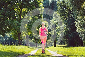 Woman running down a path on meadow with weight dumbbells