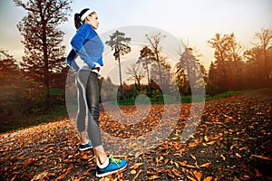 Woman running in the early evening autumn leaves