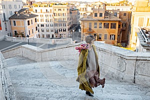 Woman running on famous Spanish steps on background of old town in Rome
