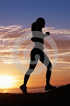 Woman running, fitness on beach and sunset for workout, outdoor training and body health in shadow or a silhouette