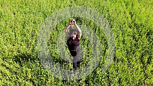 Woman running and jumping in a green field outdoors, happiness concept, freedom, inspirational, shot from drone, top