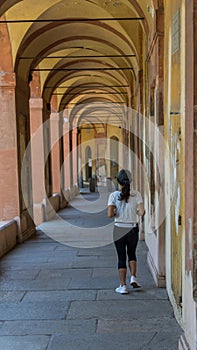 Woman running through long Portico in black pants and sneakers