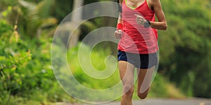 Woman running at morning tropical forest trail