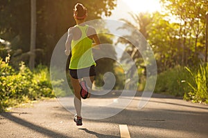 Woman running on morning tropical forest trail