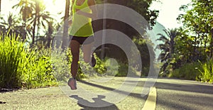 Woman running on morning tropical forest trail