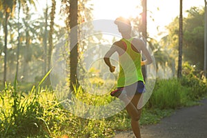 Woman running on morning tropical forest trail